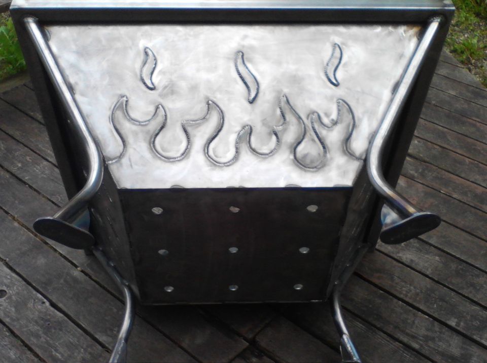 metal fire pit with flame cutouts on the side, sitting on a wooden deck