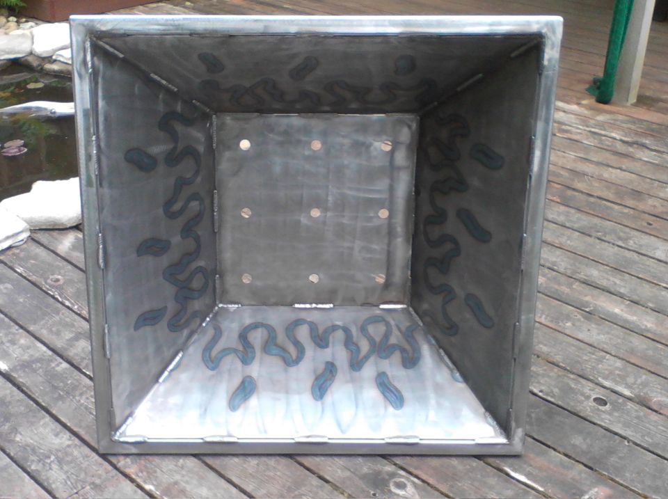 Interior view of a square metal fire pit with decorative flame-like patterns