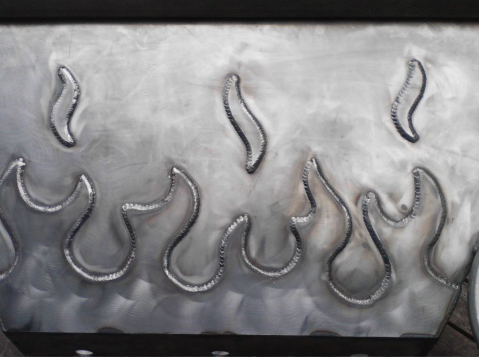 Brushed metal panel with welded flame shapes