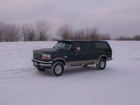 1995 Ford Bronco - Dark green 1995 Ford Bronco sits in a snow-covered landscape under an overcast sky.