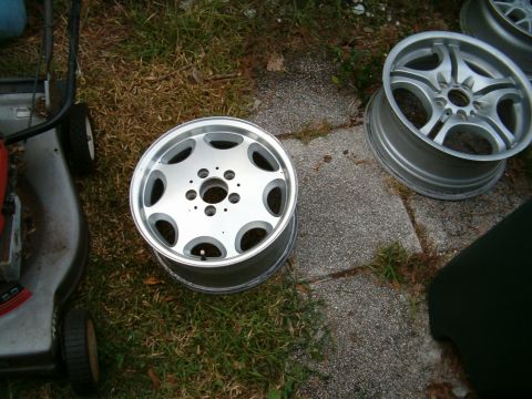 1991 Ford Bronco - Two aluminum alloy wheels are visible on the grass beside a lawnmower.