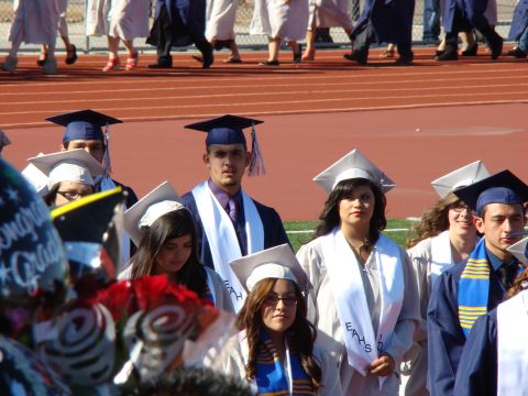 1989 Ford Bronco - Graduates in caps and gowns are seen at a ceremony, with a track and bleachers in the background.