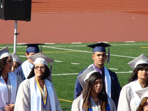 1989 Ford Bronco - Graduates in caps and gowns stand on a football field during a ceremony.