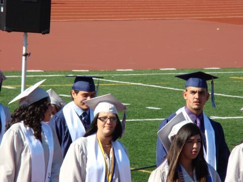 1989 Ford Bronco - Graduates in caps and gowns stand on a football field during a ceremony.