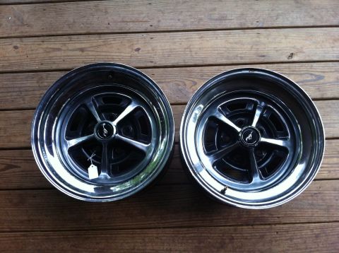 1979 Ford Ranchero - Two chrome wheels with black spokes are displayed on a wooden surface.
