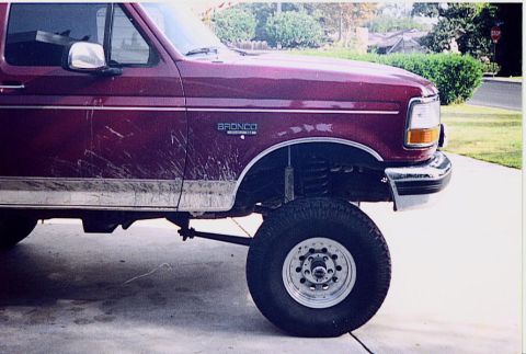 1992 Ford Bronco - Maroon 1992 Ford Bronco shows its front passenger side with aftermarket wheels and suspension modifications.