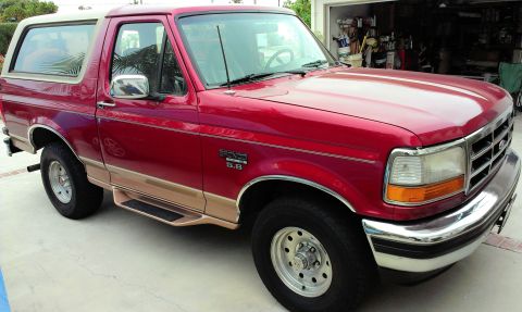 1994 Ford Bronco - This red 1994 Ford Bronco is parked outside a garage.