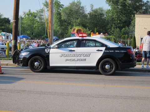 1991 Ford LTD Crown Victoria - black and white Johnston Police Ford Taurus patrol sedan parked along a sunny street at a community event.