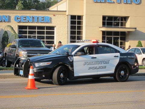 1991 Ford LTD Crown Victoria - black and white Johnston Police Ford Taurus interceptor parked by an orange cone in front of a tan building.