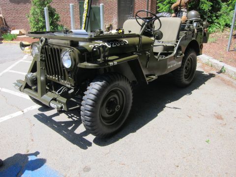 1991 Ford LTD Crown Victoria - olive drab military jeep with folded windshield and front bumper rollers parked in a paved lot.