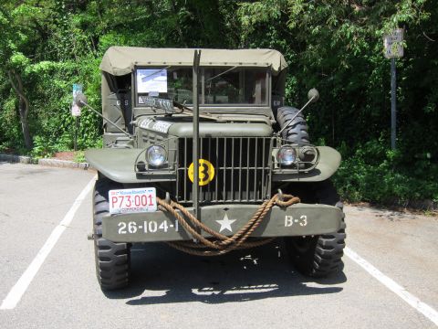 1991 Ford LTD Crown Victoria - Head-on view of an olive drab military truck showing grille, yellow circle emblem and 26-104-1 bumper markings.
