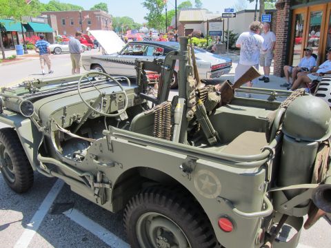 1991 Ford LTD Crown Victoria - Detail of an olive drab military jeep fitted with a mounted machine gun, ammo belt and white star at a car show.