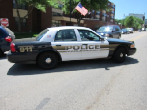 1991 Ford LTD Crown Victoria - Side profile of a black-and-white Marlborough police sedan marked POLICE 911, parked on a town street near a flagpole.