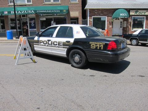 1991 Ford LTD Crown Victoria - black-and-white Marlborough police sedan marked EMERGENCY 911 parked on a street beside a folding barricade sign.
