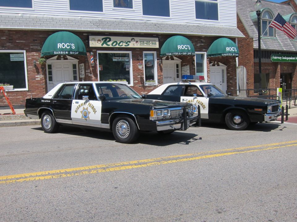 Two vintage Highway Patrol black and white sedans at the curb