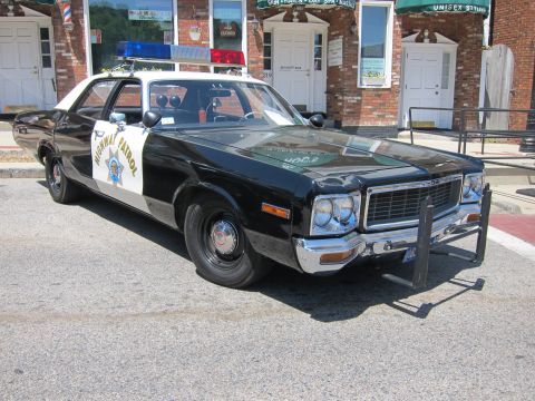 1991 Ford LTD Crown Victoria - Front three-quarter view of a vintage black-and-white Dodge Highway Patrol sedan with a push bar, parked at a curb.