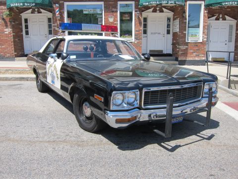 1991 Ford LTD Crown Victoria - Front view of a vintage black-and-white Dodge Highway Patrol sedan, DODGE lettering on the grille, parked at a curb.