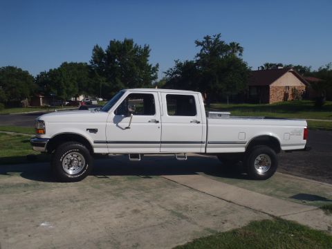 1997 Ford F-350 - A white 1997 Ford F-350 crew cab pickup truck is shown from the side on a sunny day.
