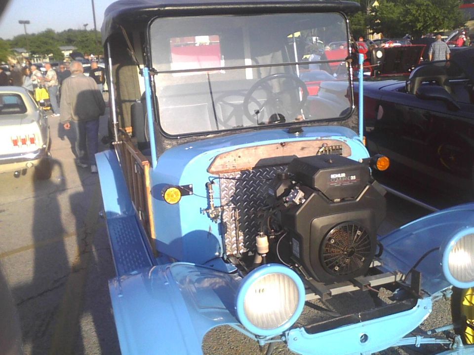 Custom light blue truck with a Kohler engine visible in front. Other vehicles and people are in the background