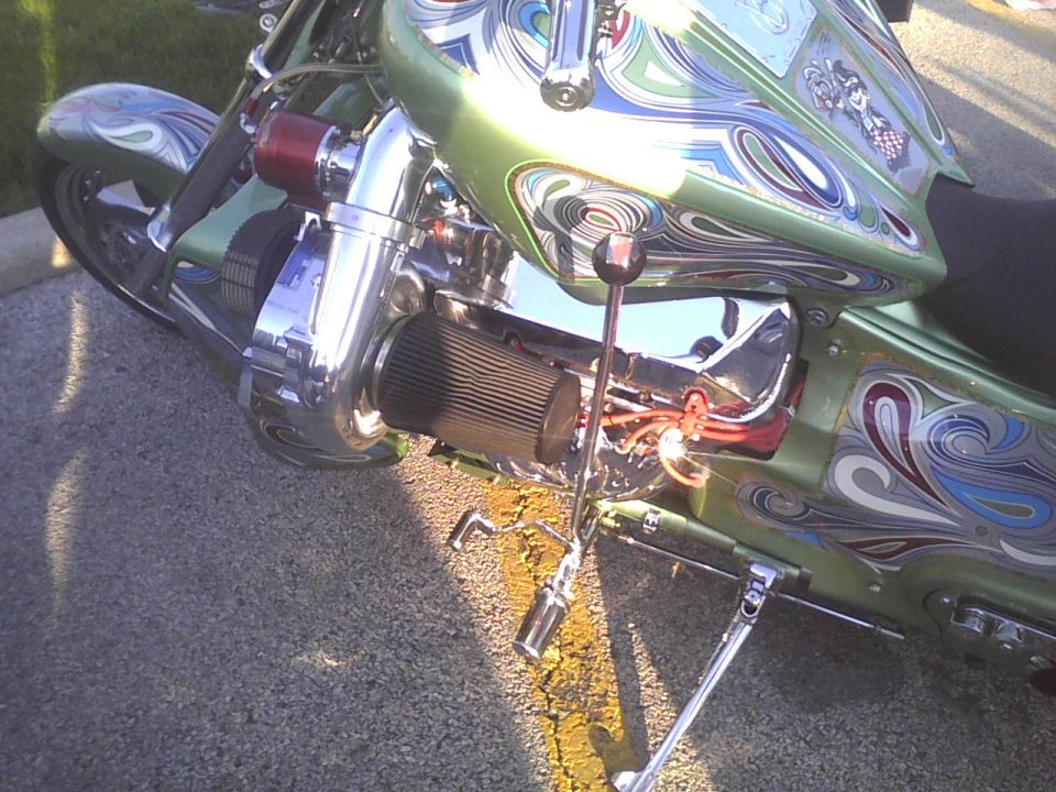 Chopper motorcycle with custom green paint, airbrushed designs, and a visible turbocharger and air filter