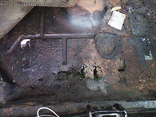 1975 Chevrolet Chevelle - Close-up of a heavily rusted floor pan, showing significant deterioration.