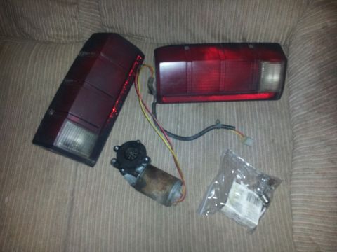 1988 Ford Bronco - Two red taillights and a motor are displayed on a couch, possibly for a 1988 Ford Bronco.