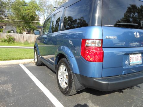 1996 Ford F-150 - The rear of a blue Honda Element is visible, parked in a lot with a wooden fence in the background.