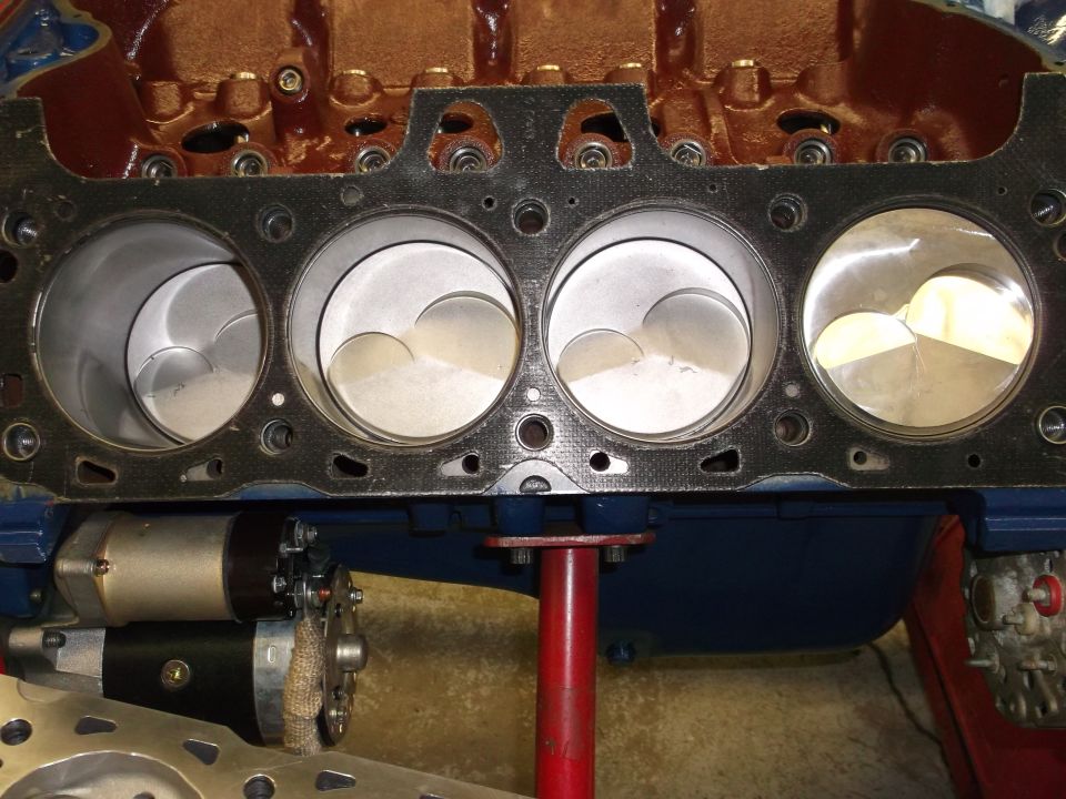Engine block with four pistons visible, a starter motor attached, and SuperMotors.net logo