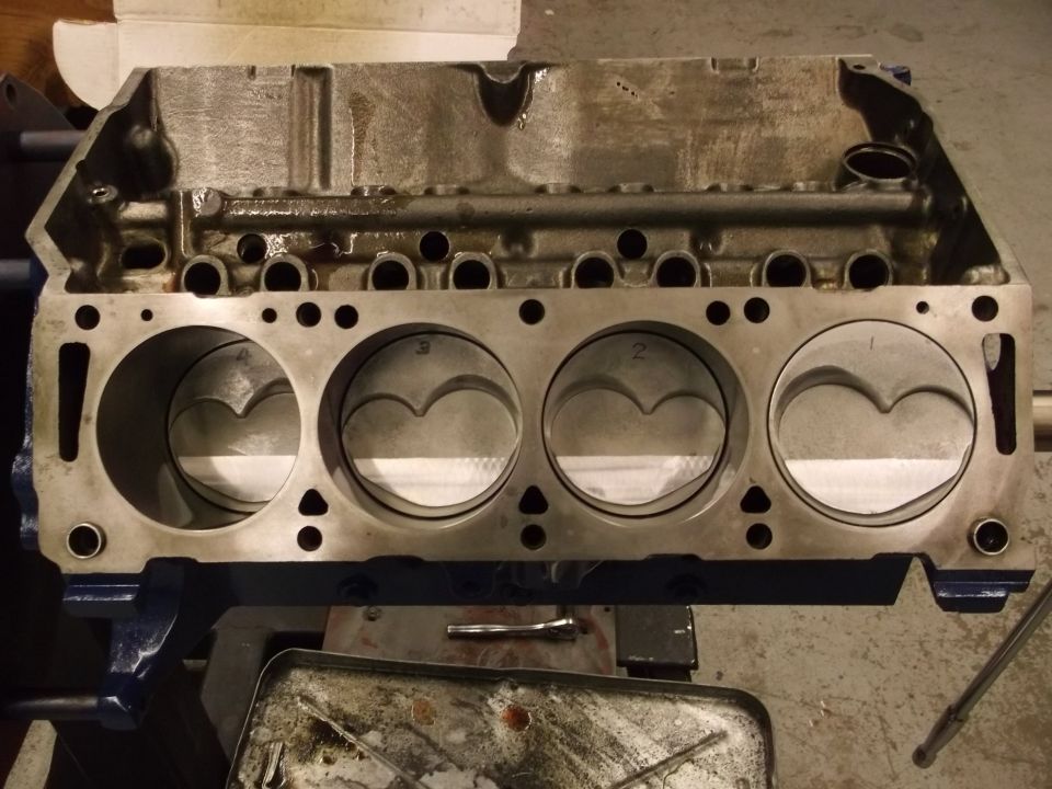Engine block with four pistons visible, held in a vise