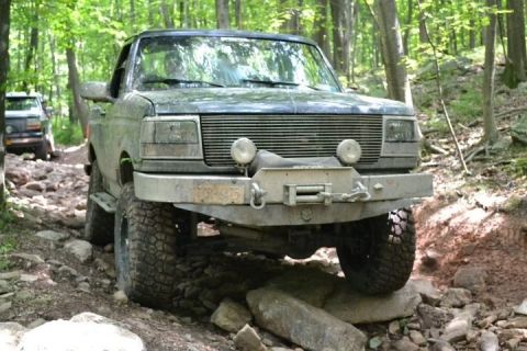 1995 Ford Bronco - This 1992 Ford Bronco is tackling a challenging rocky trail in the woods, with another Bronco following behind.
