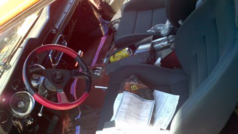 1987 Ford Bronco - The interior of a vehicle shows a cluttered passenger seat with papers and a soda can.