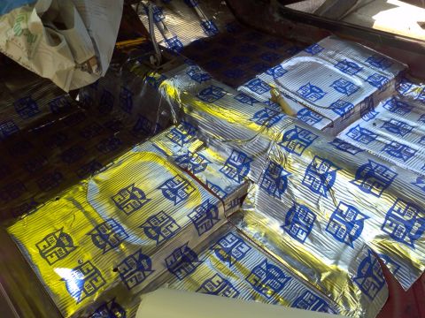 1987 Ford Bronco - Soundproofing material is being installed on the floor of a vehicle's interior.
