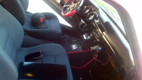 1987 Ford Bronco - The interior of a vehicle is shown, blue seats, a black baseball cap, and visible wiring near the dashboard.