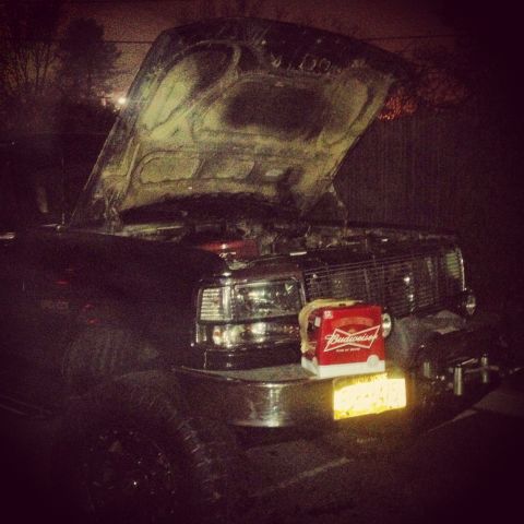 1995 Ford Bronco - 1995 Ford Bronco with hood open, Budweiser box on front bumper at night.