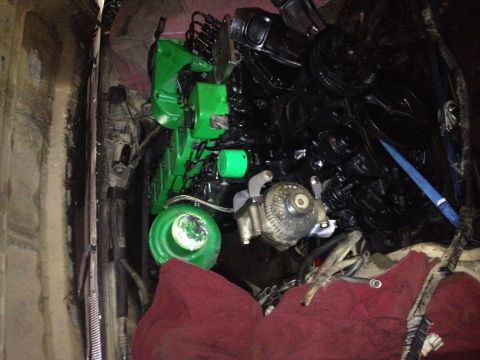 1995 Ford Bronco - Engine bay components, including a green painted section and black engine parts, are visible along with an alternator and the Supermotors l…