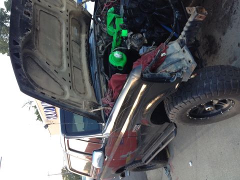 1995 Ford Bronco - A dark-colored SUV (rotated image) with its hood raised, showing an engine bay mid-project with a bright green intake/valve cover component…