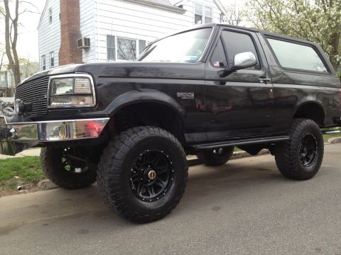 1995 Ford Bronco - This black lifted 1995 Ford Bronco is shown from a 3q-front angle, highlighting its stance and off-road tires.
