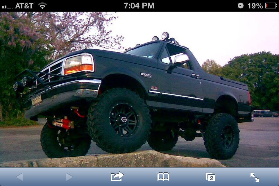 Lifted black Ford Bronco parked on a curb, front end is angled up