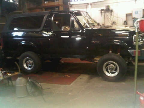 1995 Ford Bronco - Side profile of a black 1995 Ford Bronco, appearing to be in a garage or workshop.