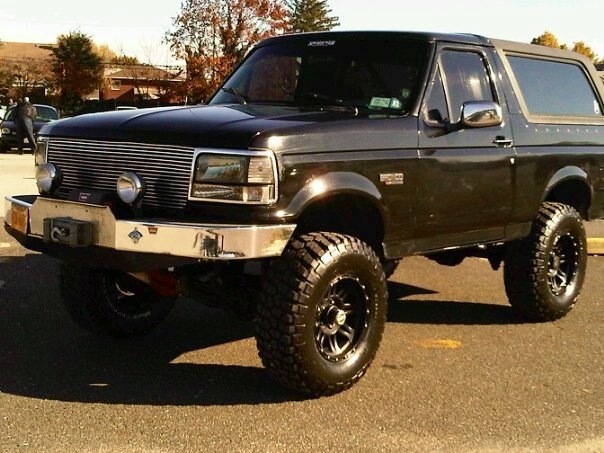 Lifted black Ford Bronco with aftermarket grille and bumper
