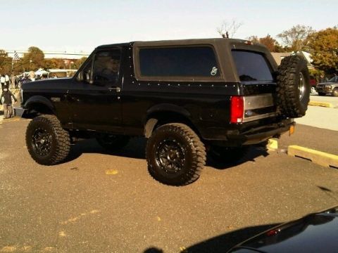 1995 Ford Bronco - This black Ford Bronco features a spare tire mounted on the rear and aftermarket wheels.