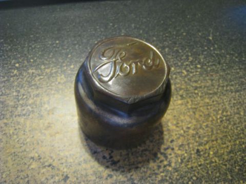 1912 Ford Model T - Close-up of a Ford script logo on a hexagonal metal part, possibly a hubcap.