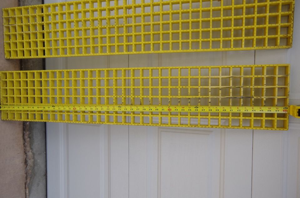 Two yellow plastic grates with a tape measure on the bottom one