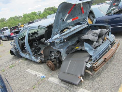 1991 Ford LTD Crown Victoria - Junkyard sedan, heavily damaged, with another vehicle in the background.