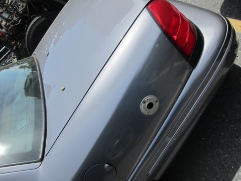 1991 Ford LTD Crown Victoria - Rear quarter panel view of a gray sedan, showing the taillight, fuel door, and a circular mounting point on the trunk lid.