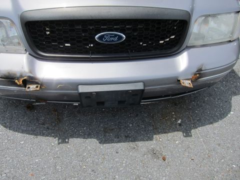 1991 Ford LTD Crown Victoria - The front grille and bumper of a silver Ford Crown Victoria show damage and rust.