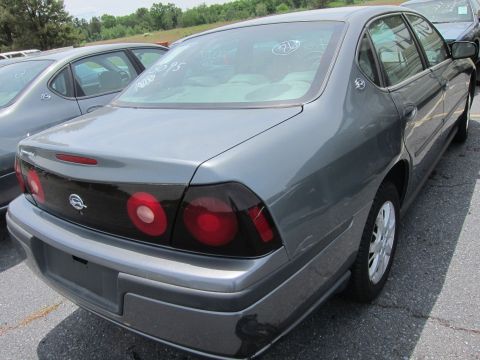 1991 Ford LTD Crown Victoria - Rear view of a gray sedan with tinted taillights and a spoiler, parked in a lot with other vehicles.
