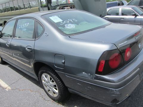 1991 Ford LTD Crown Victoria - This gray sedan has tinted taillights and visible damage to its rear bumper and quarter panel.