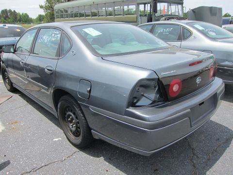 1991 Ford LTD Crown Victoria - Rear view of a dark gray sedan, possibly a Chevrolet Impala, with a damaged taillight and visible auction markings.