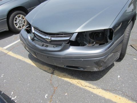 1991 Ford LTD Crown Victoria - The front end of a car shows significant damage, including a missing headlight and a dented bumper.
